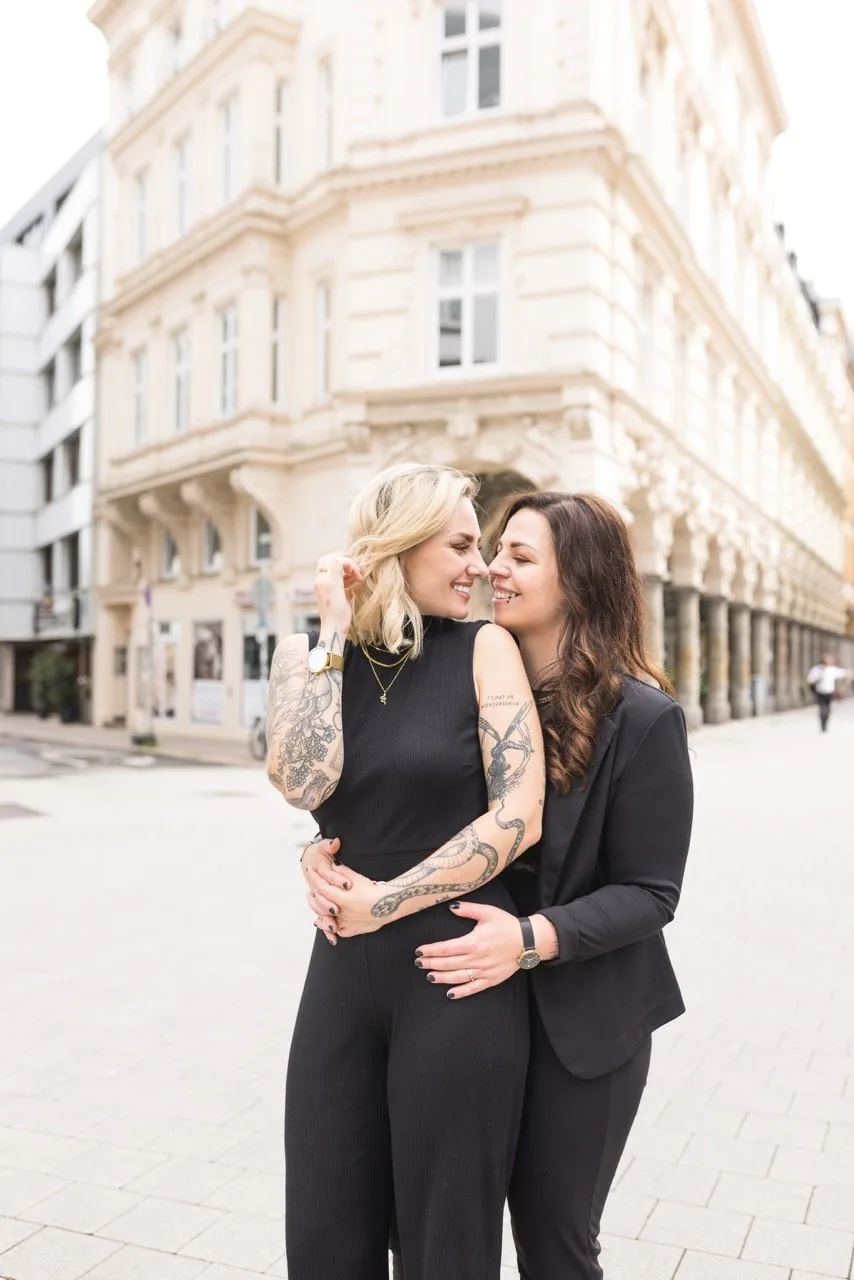 Zwei Frauen umarmen sich lachend auf einer Straße in der Innenstadt