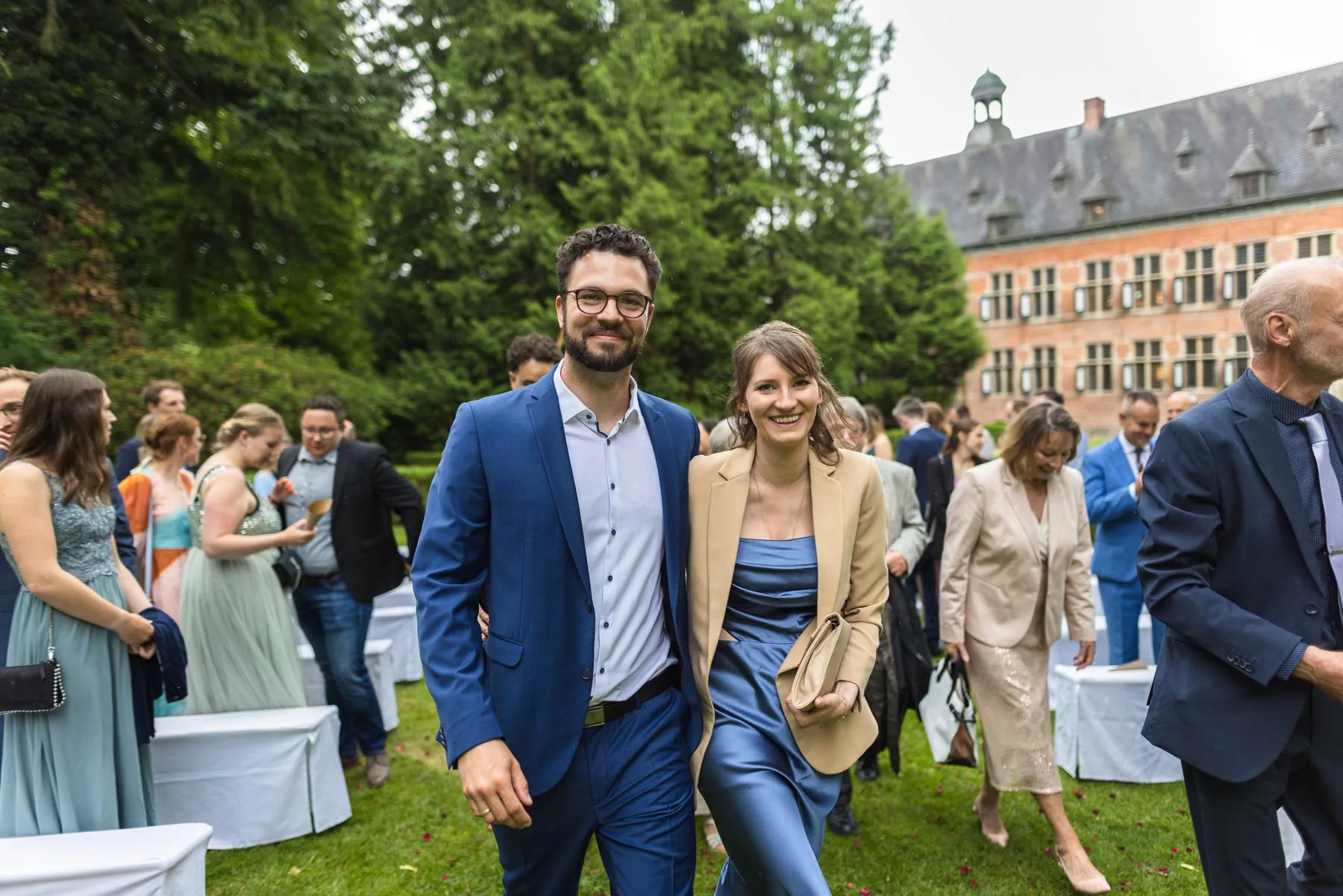 Zwei Hochzeitsgäste beim Empfang im Garten, im Hintergrund das Gutshaus