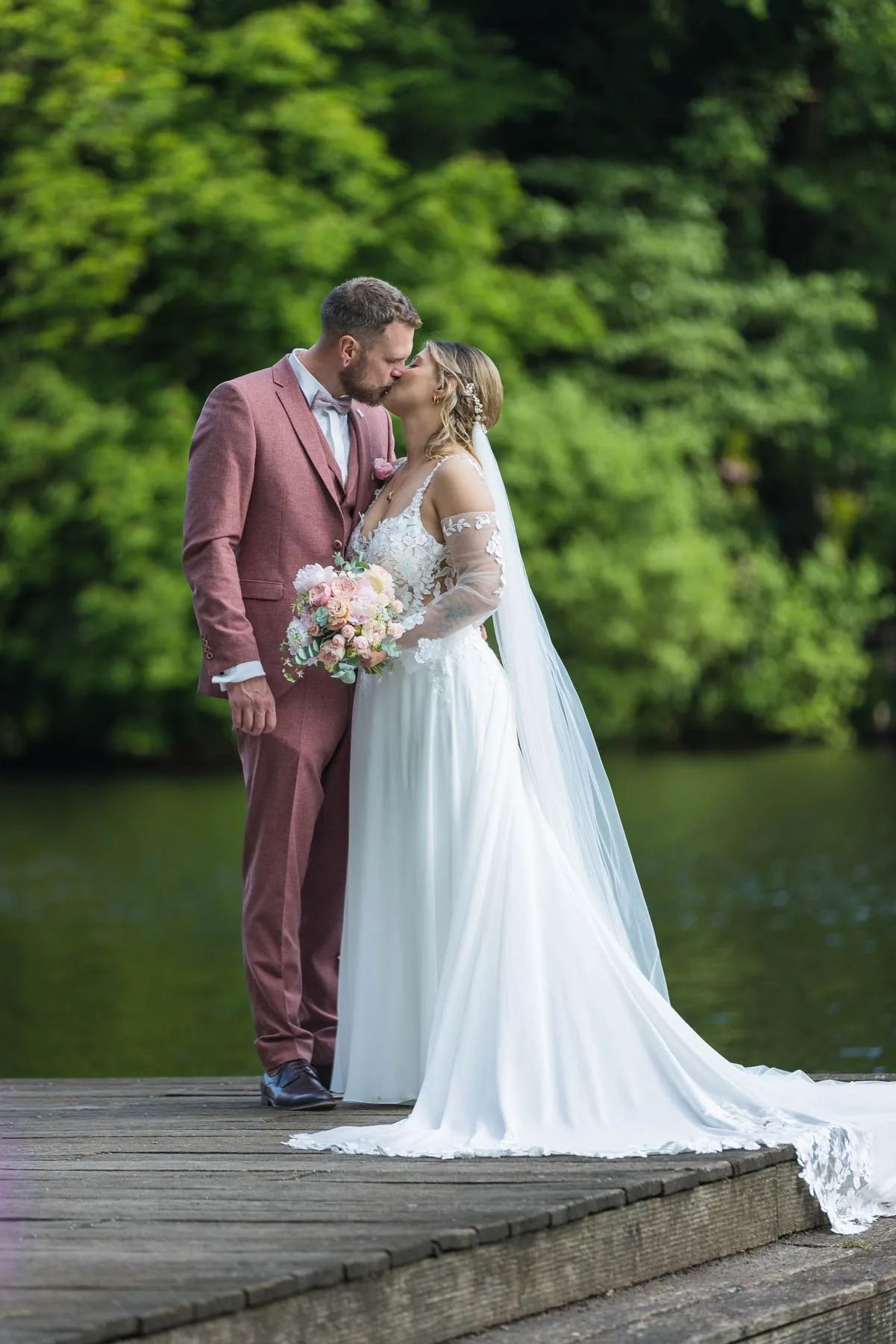 Jaci und Nils küssen sich auf einem Holzsteg am See